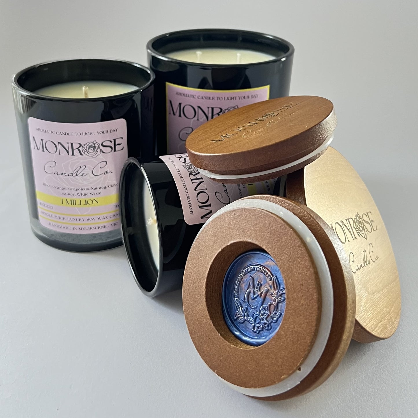 "Front view of 1 million fragrance candle collection in black jars and cotton wicks."