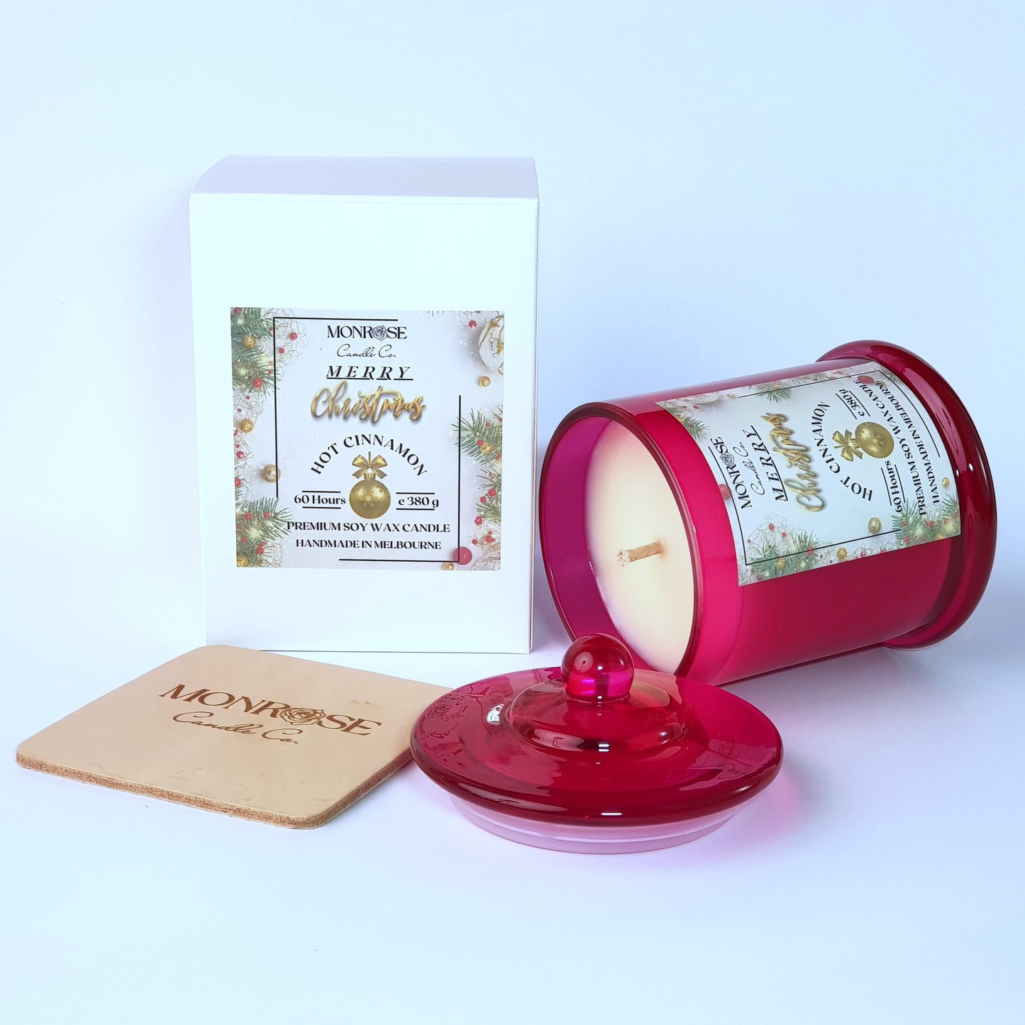 "Side view of a red jar candle with
"Hot Cinnamon" fragrance and a cotton wick, containing 380 grams of soy wax and offering 60 hours of burn time."