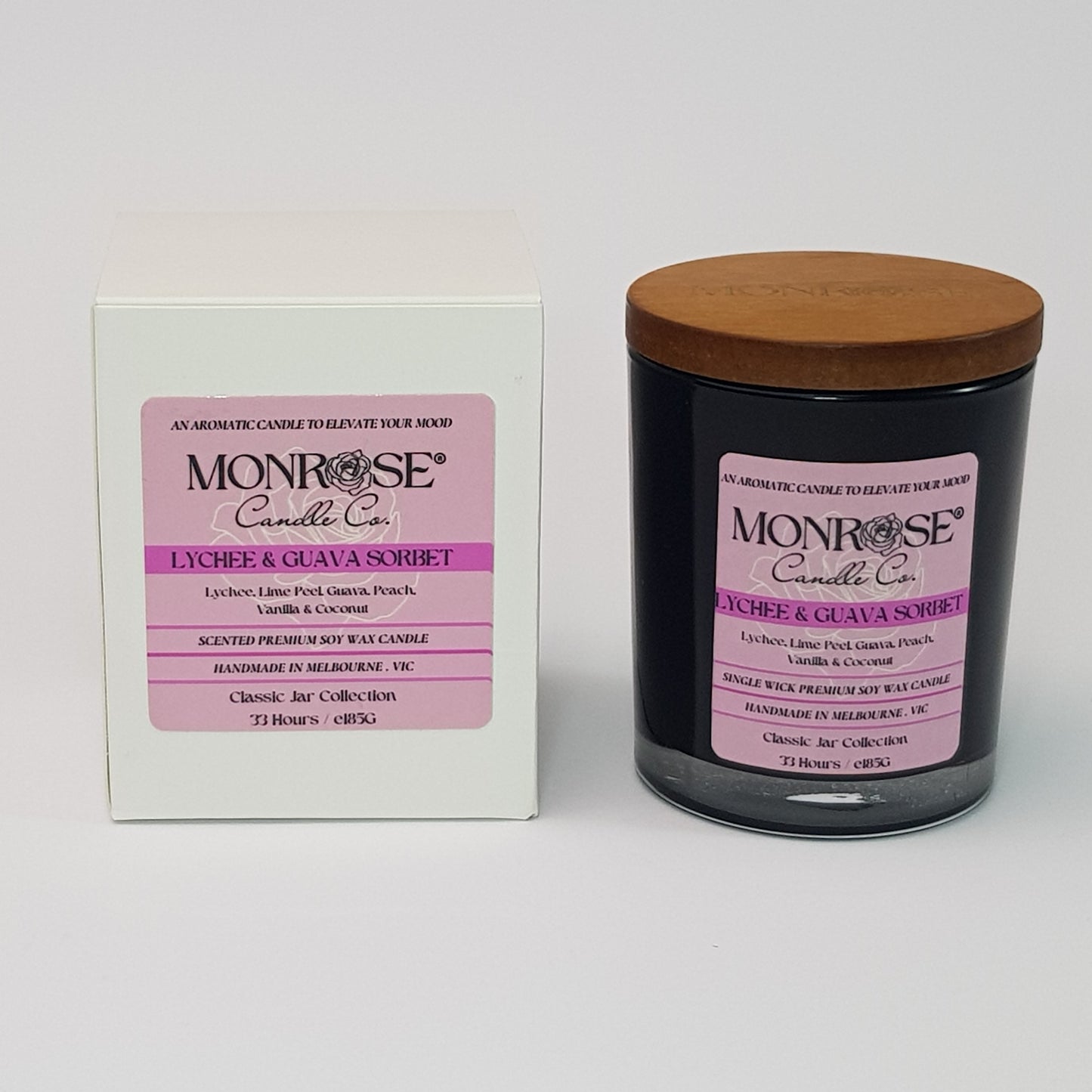 Front view of a container candle with "Lychee & guava sorbet" fragrance in black glass jar and a cotton wick, containing 185 grams of soy wax and offering 33 hours of burn time.