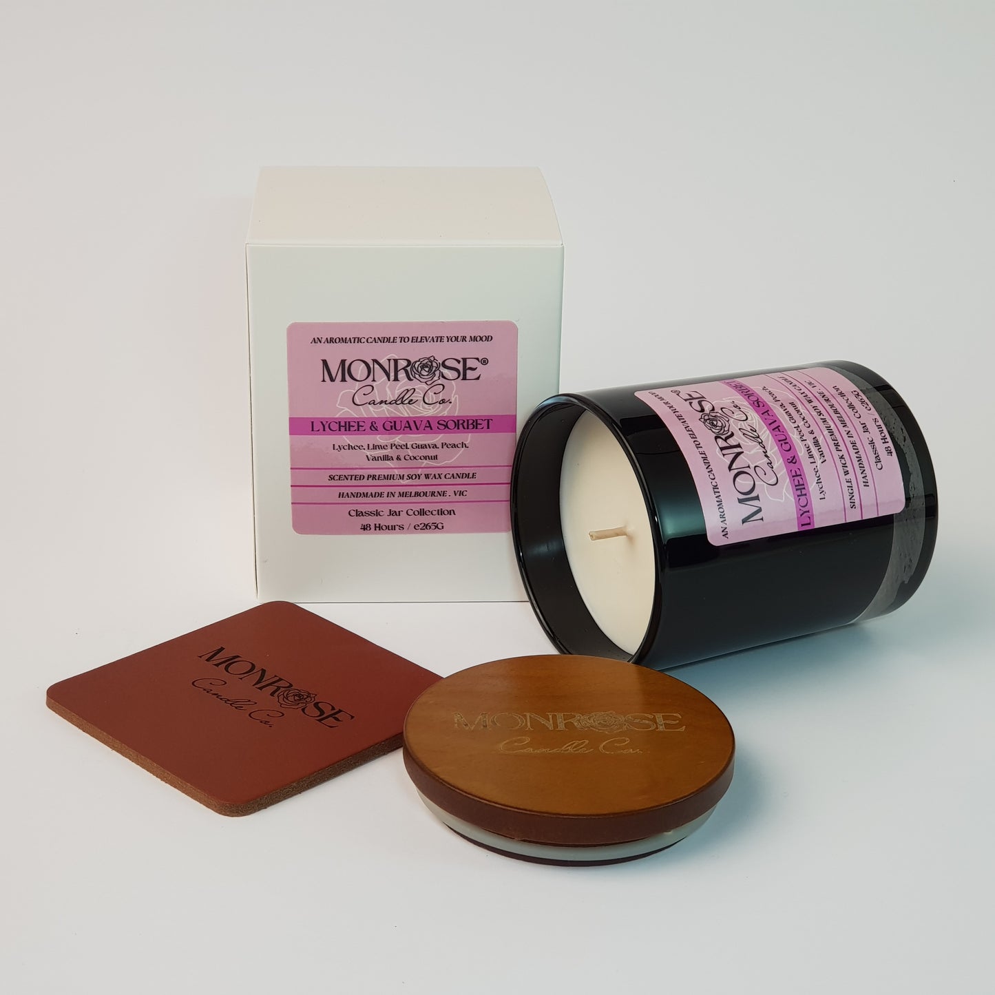 Side view of a container candle with "Lychee & guava sorbet" fragrance in black glass jar and a cotton wick, containing 265 grams of soy wax and offering 48 hours of burn time.