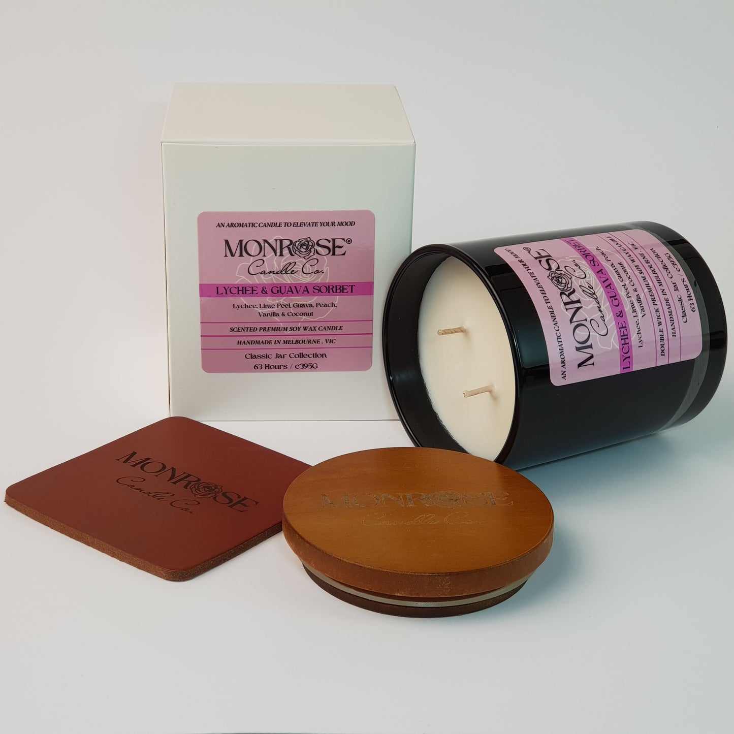 Side view of a container candle with "Lychee & guava sorbet" fragrance in black glass jar and a cotton wick, containing 395 grams of soy wax and offering 63 hours of burn time.
