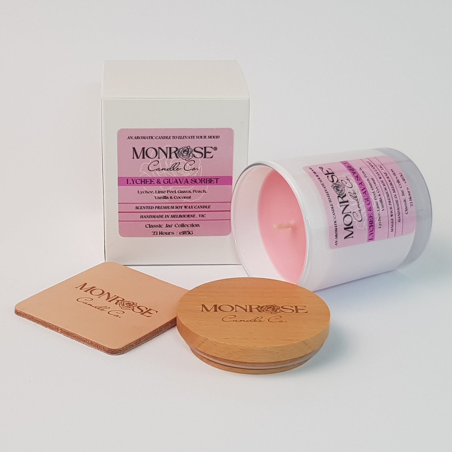 Side view of a container candle with "Lychee & guava sorbet" fragrance in white glass jar and a cotton wick, containing 185 grams of soy wax and offering 33 hours of burn time.