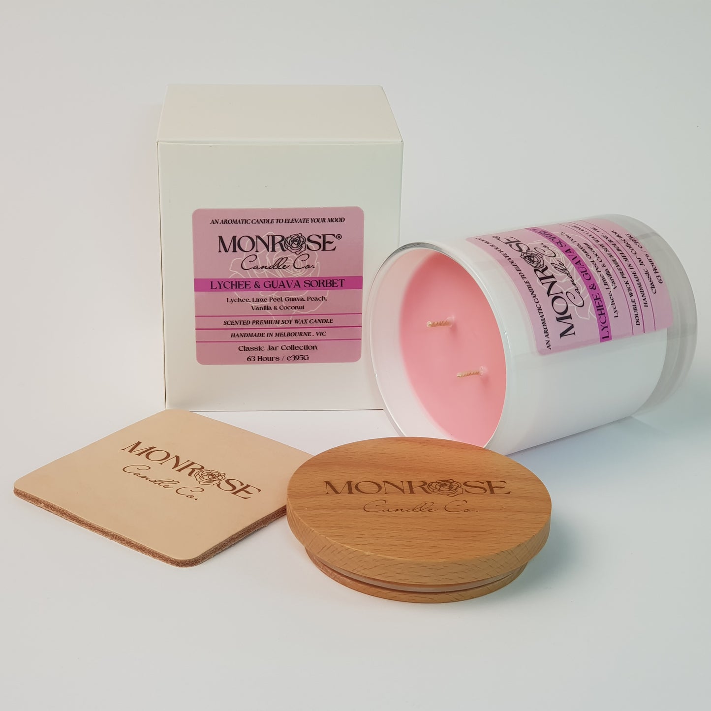 Side view of a container candle with "Lychee & guava sorbet" fragrance in black glass jar and double cotton wicks, containing 395 grams of soy wax and offering 63 hours of burn time.