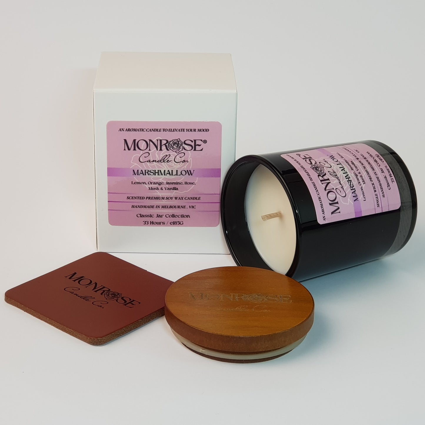 Side view of a container candle with "Marshmallow" fragrance in black glass jar and a cotton wick, containing 185 grams of soy wax and offering 33 hours of burn time.