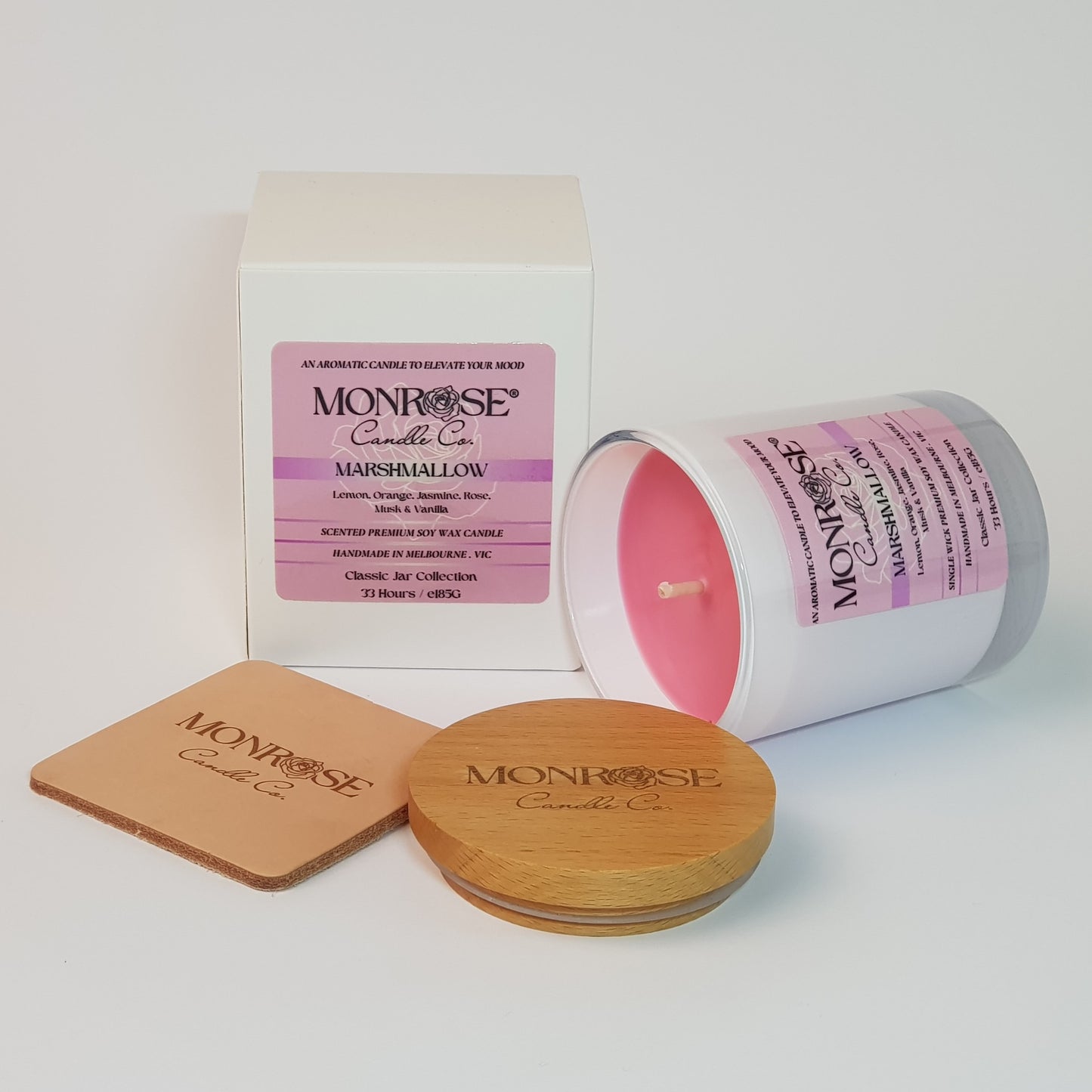Side view of a container candle with "Marshmallow" fragrance in white glass jar and a cotton wick, containing 185 grams of soy wax and offering 33 hours of burn time.