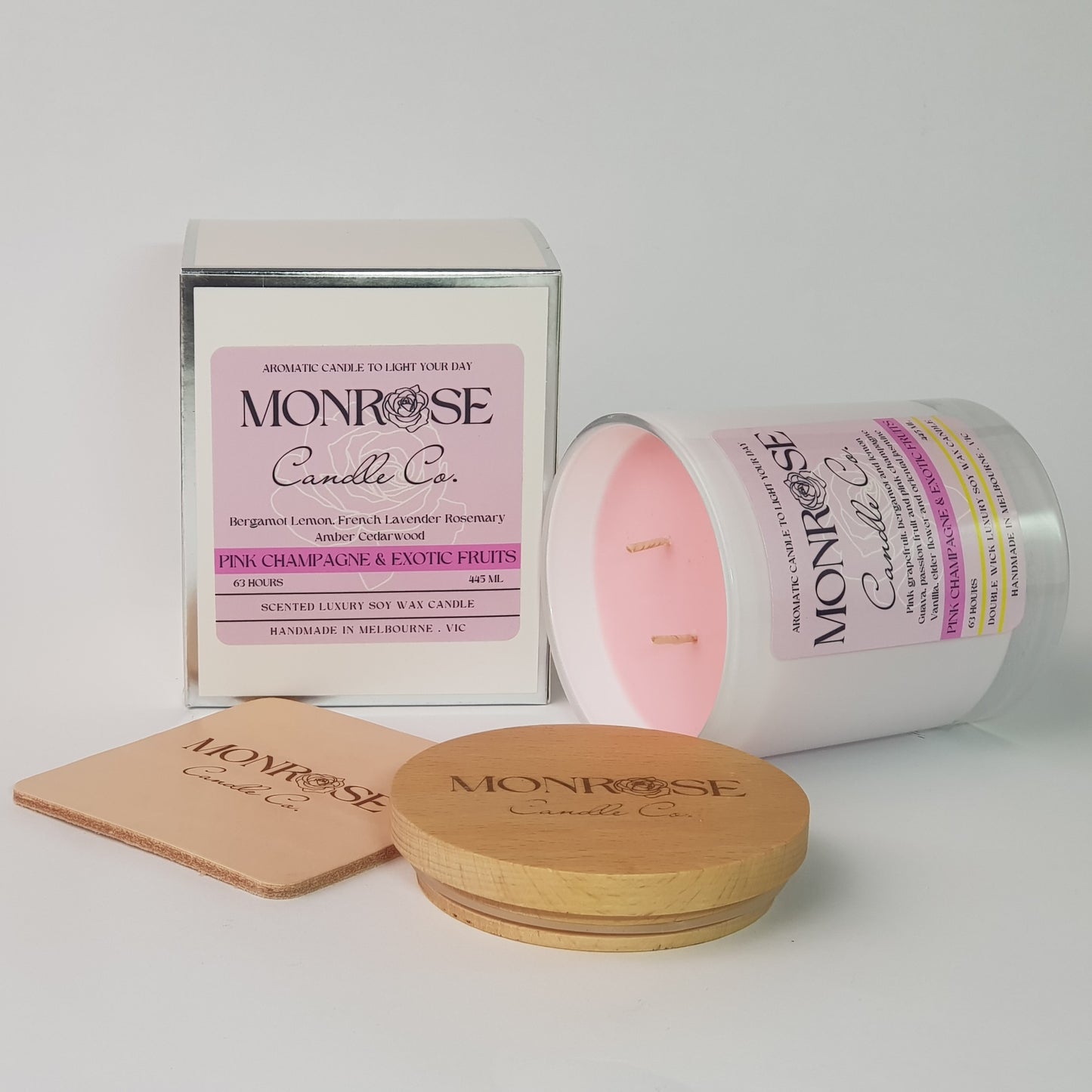 Side view of a white jar candle with "Pink champagne & exotic fruits" fragrance and double cotton wick, containing 395 grams of soy wax and offering 63 hours of burn time.