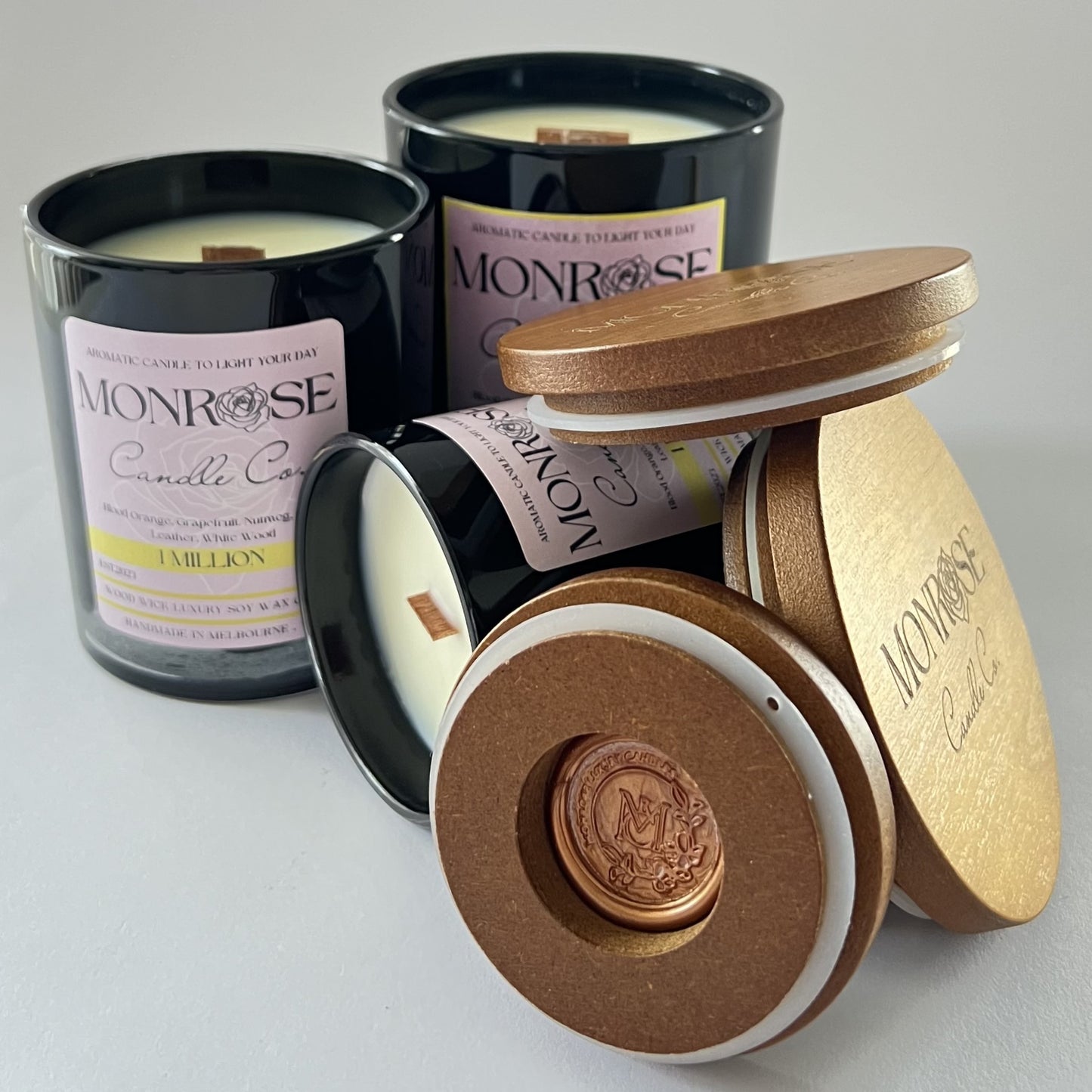 "Front view of 1 million fragrance candle collection in black jars and  wood wicks."