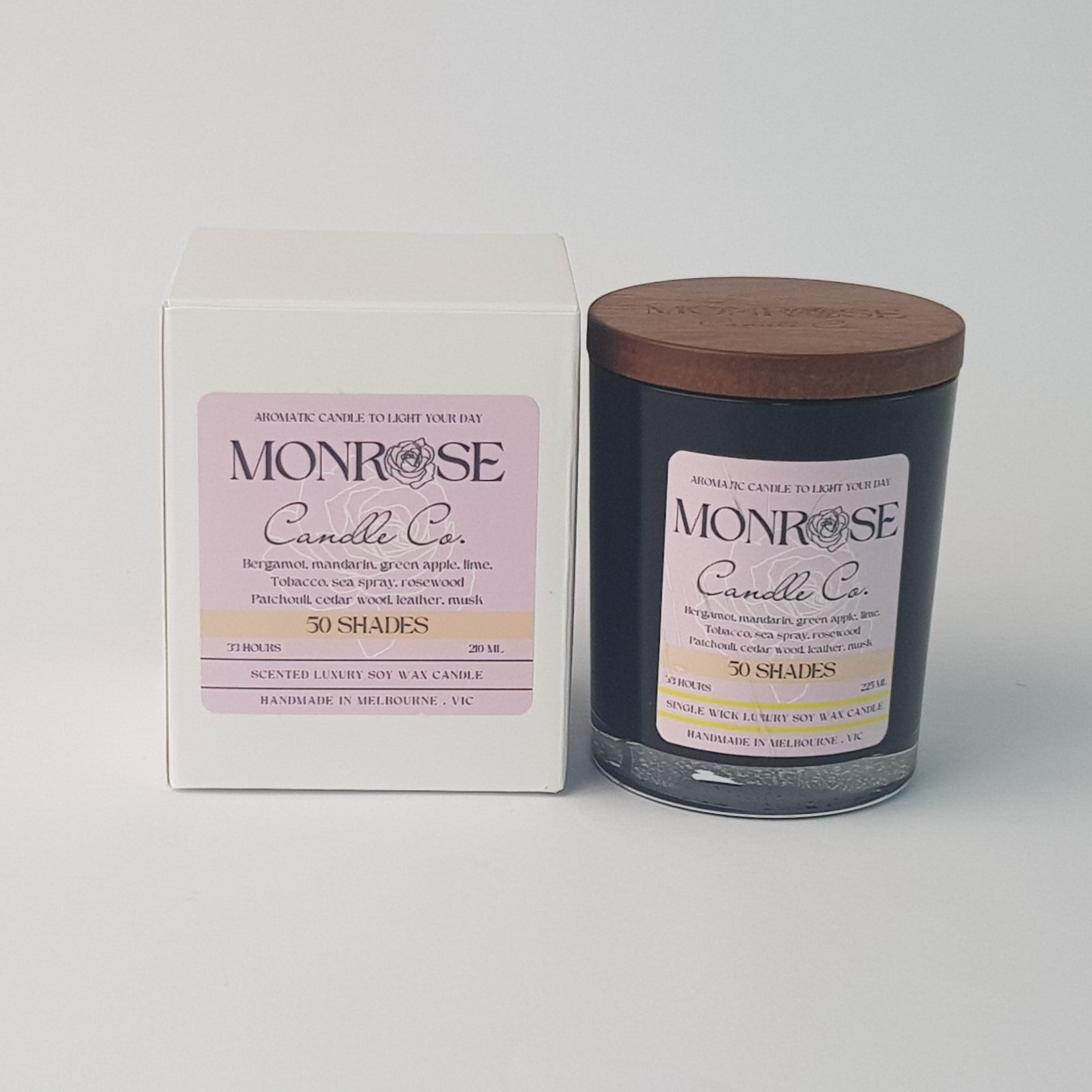 Front view of a container candle with "50 Shades" fragrance in black glass jar and a cotton wick, containing 185 grams of soy wax and offering 33 hours of burn time.