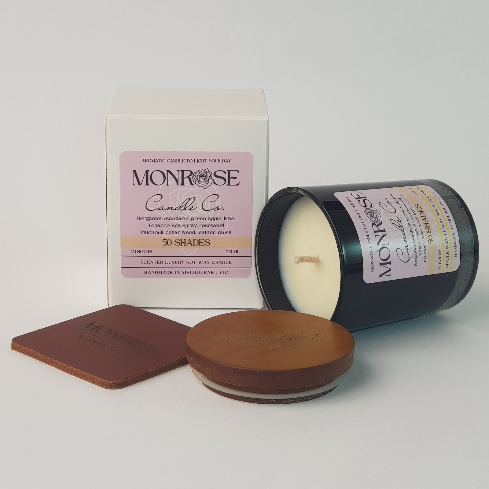 Side view of a black jar candle with "50 Shades" fragrance and a cotton wick, containing 185 grams of soy wax and offering 33 hours of burn time.