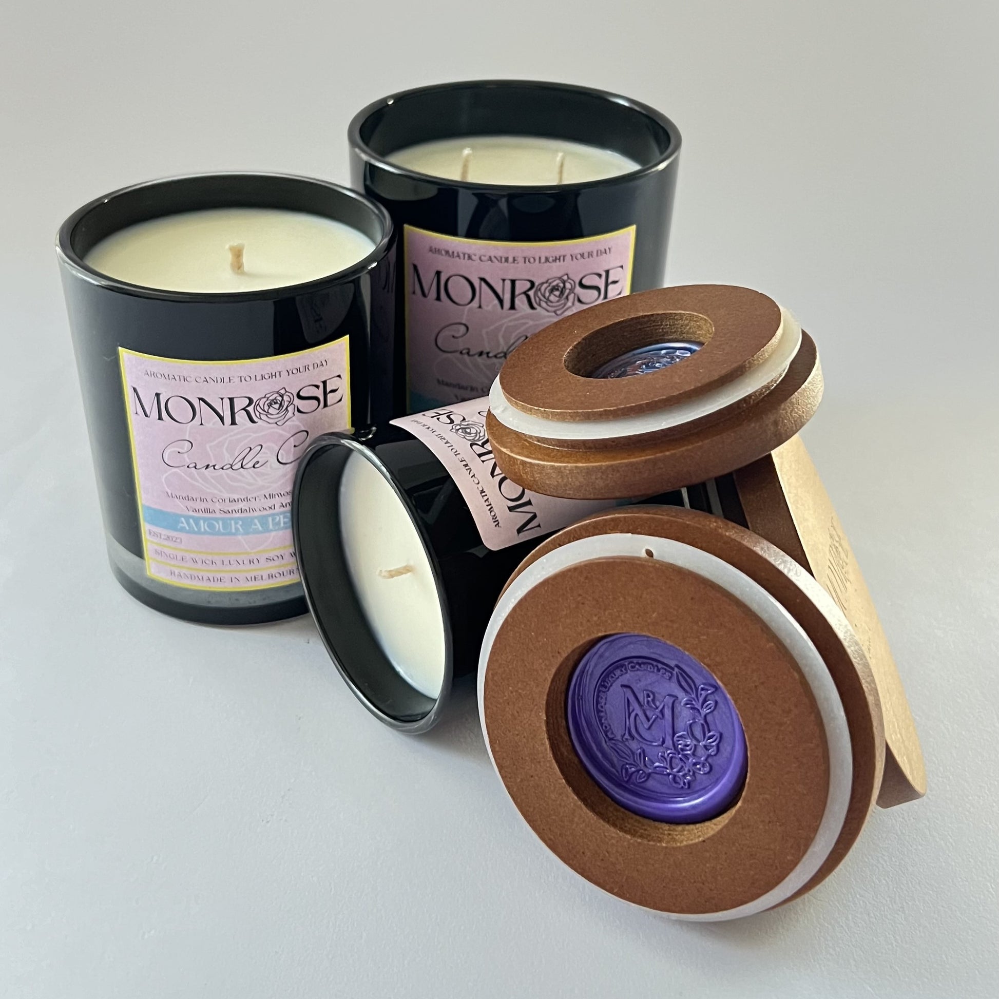Front view of black jar candle collection with "Amour a Paris" fragrance and cotton wick.