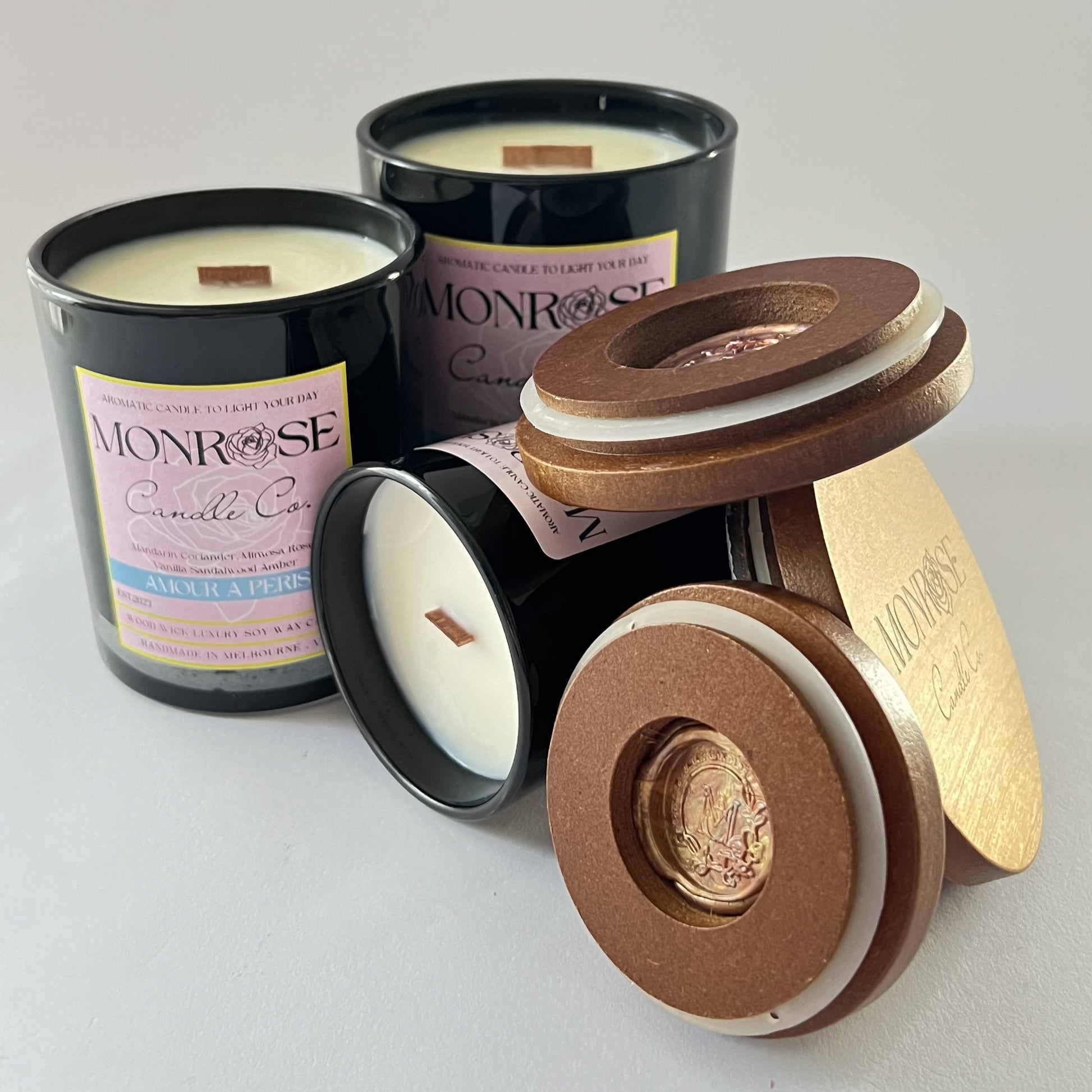 Front view of black jar candle collection with "Amour a Paris" fragrance and wood wick.