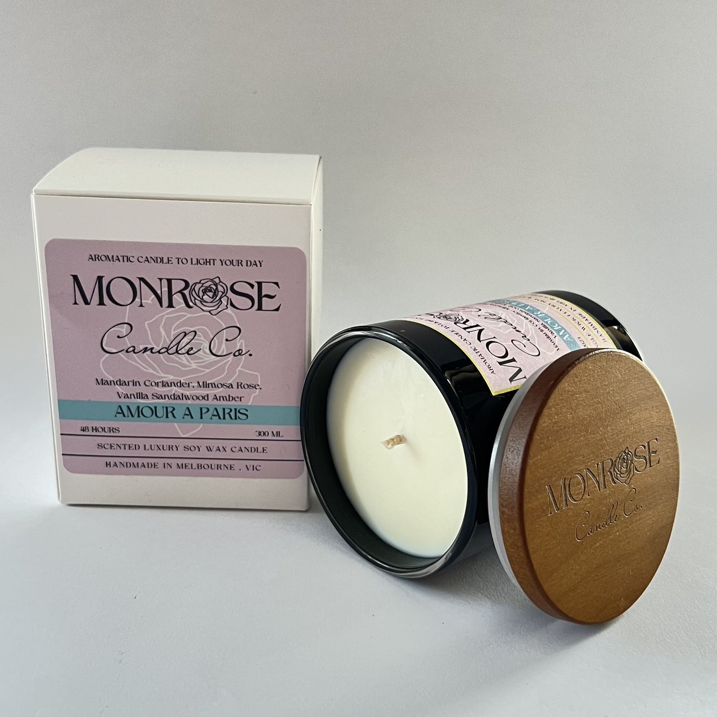 Side view of a black jar candle with "Amour A Paris" fragrance and two cotton wicks, containing 265 grams of soy wax and offering 48 hours of burn time.