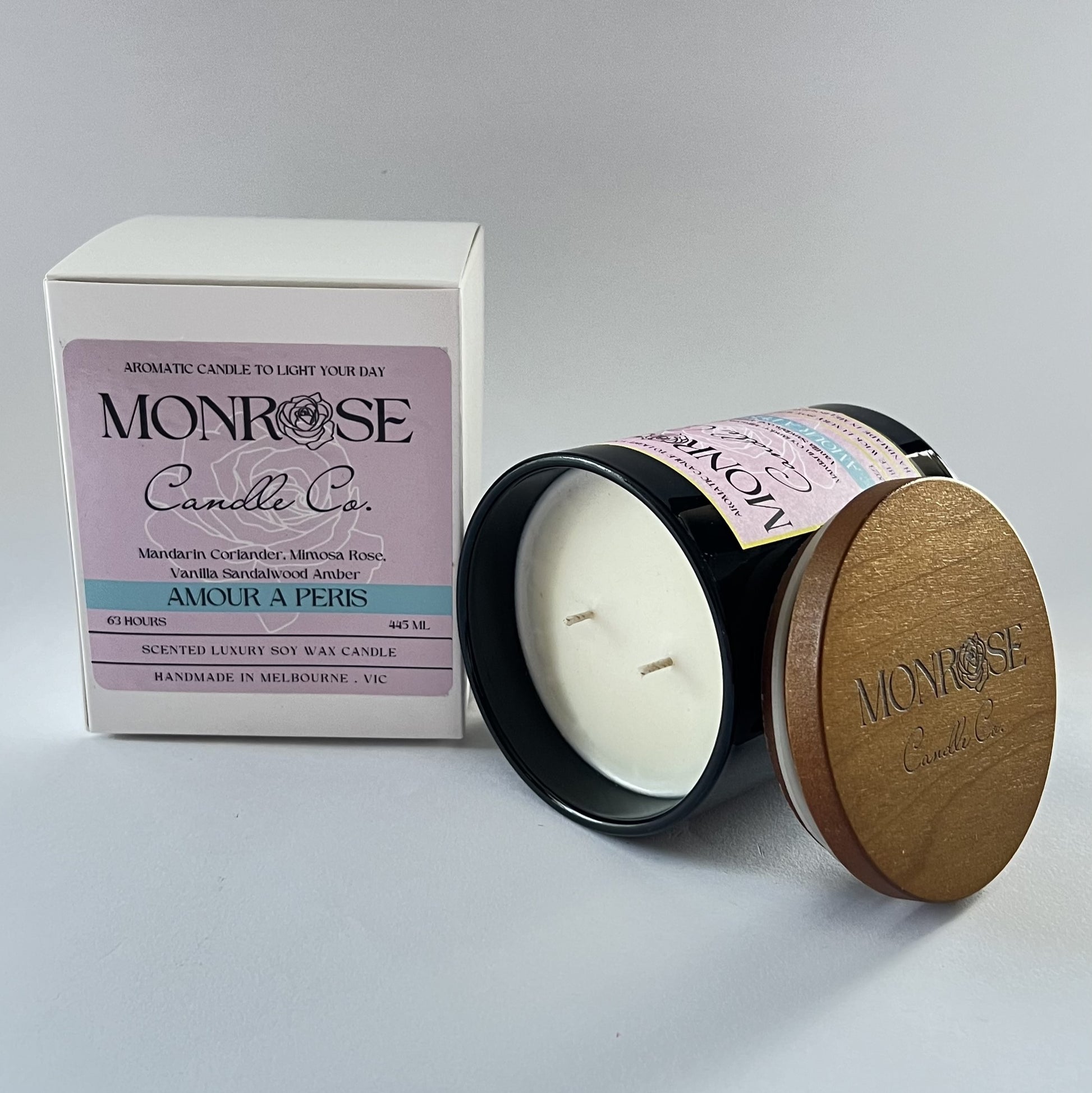 Side view of a black jar candle with "Amour A Paris" fragrance and two cotton wicks, containing 395 grams of soy wax and offering 63 hours of burn time.
