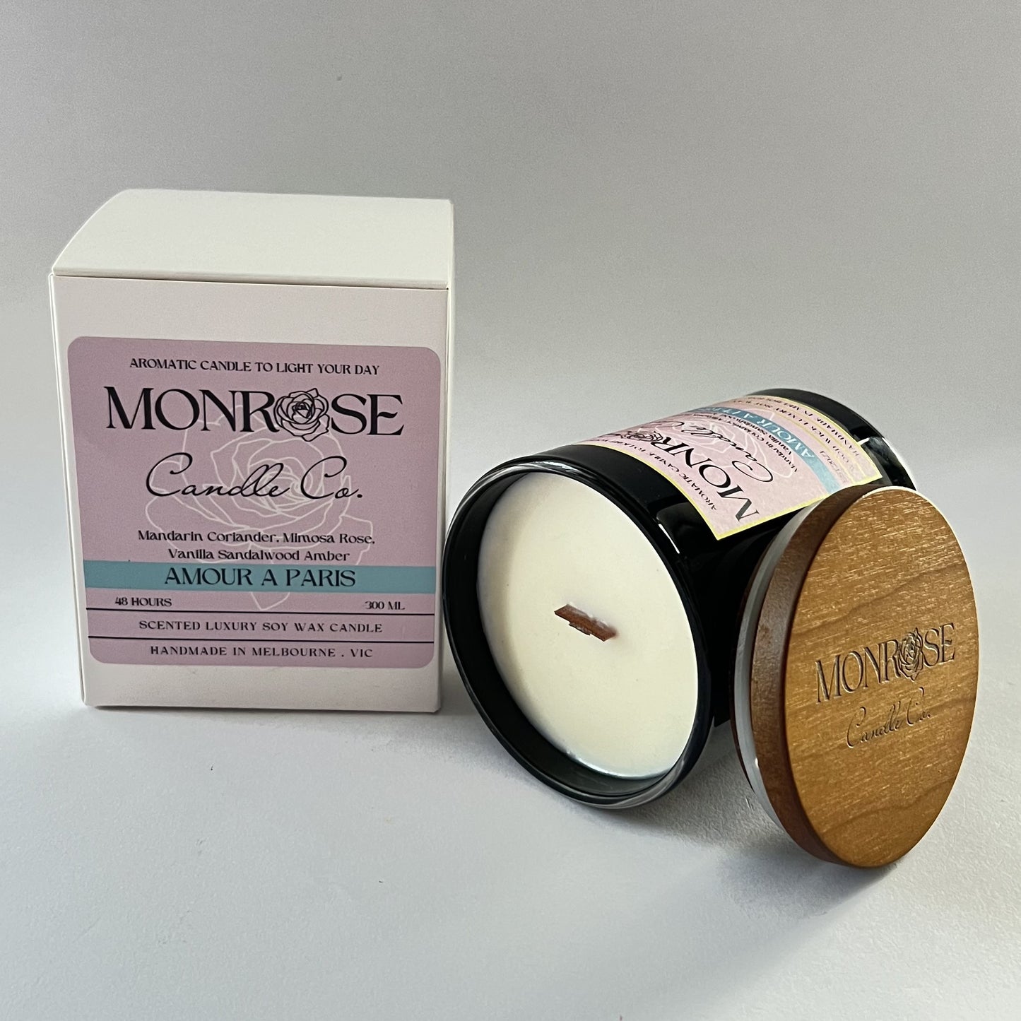 Side view of a black jar candle with "Amour A Paris" fragrance and two wood wicks, containing 265 grams of soy wax and offering 48 hours of burn time.