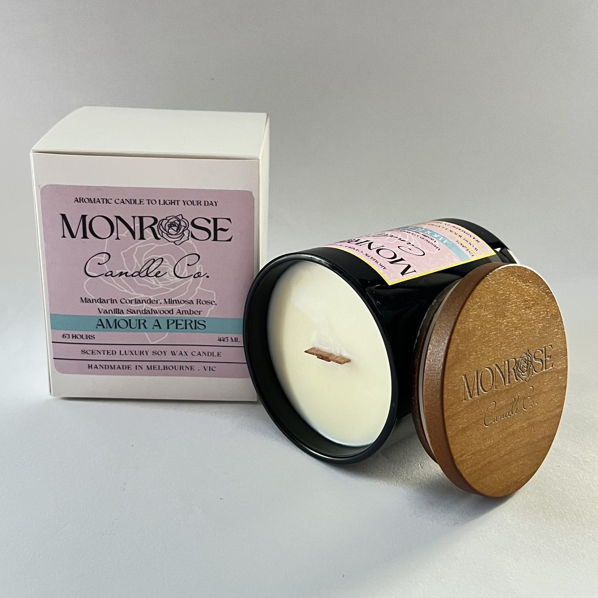 Side view of a black jar candle with "Amour A Paris" fragrance and two cotton wicks, containing 385 grams of soy wax and offering 63 hours of burn time.