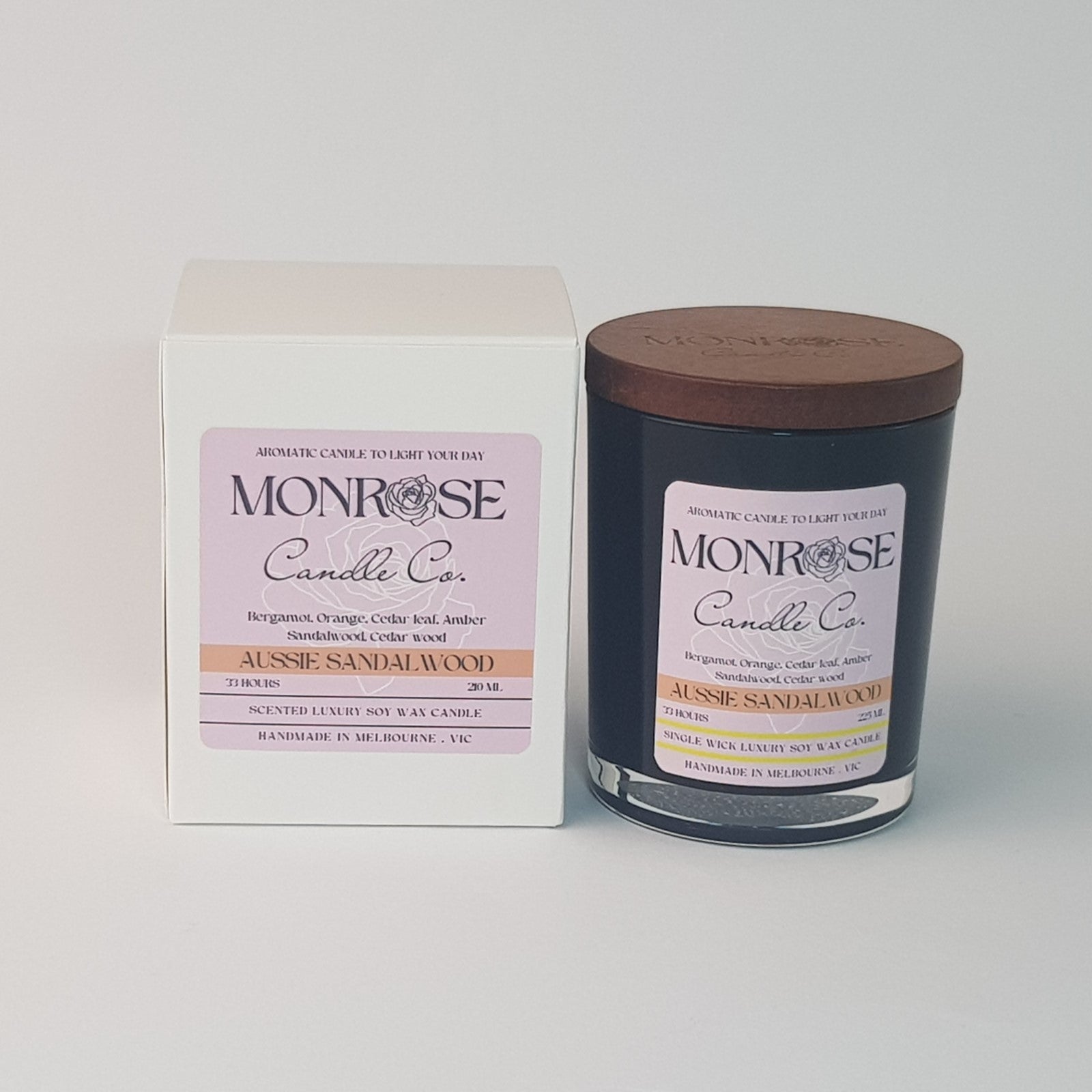 Front view of a container candle with "Australian Sandalwood" fragrance in black glass jar and a cotton wick, containing 185 grams of soy wax and offering 33 hours of burn time.