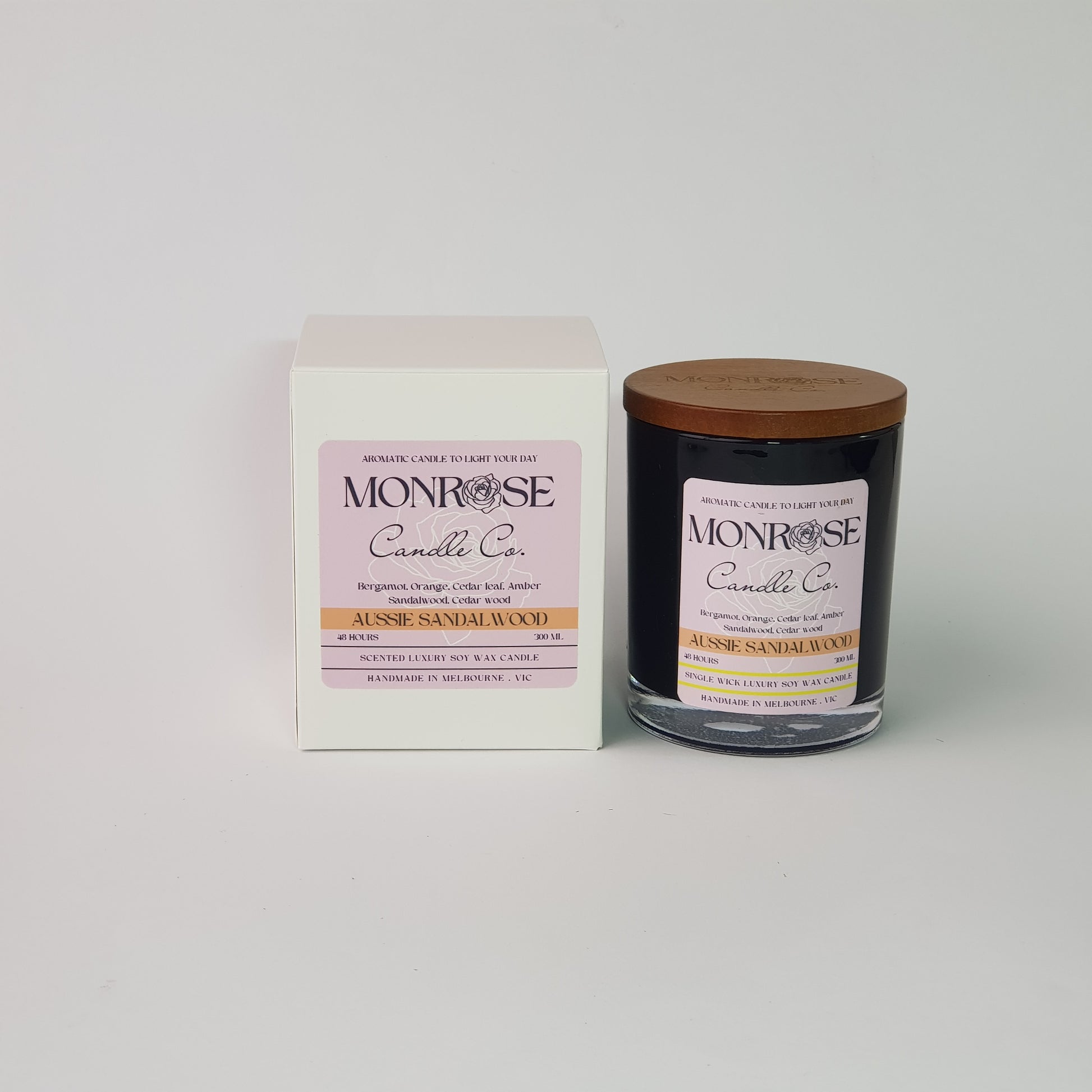 Front view of a container candle with "Australian Sandalwood" fragrance in black glass jar and a cotton wick, containing 265 grams of soy wax and offering 48 hours of burn time.