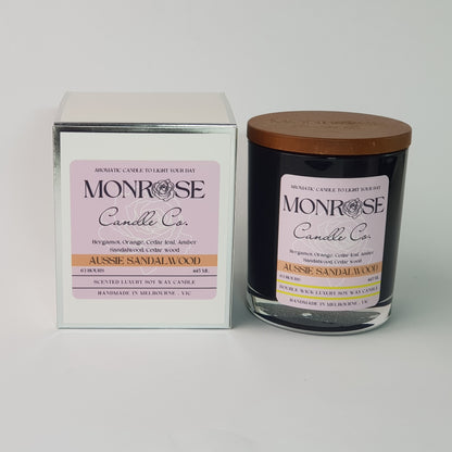 Front view of a container candle with "Australian Sandalwood" fragrance in black glass jar and a cotton wick, containing 395 grams of soy wax and offering 63 hours of burn time.