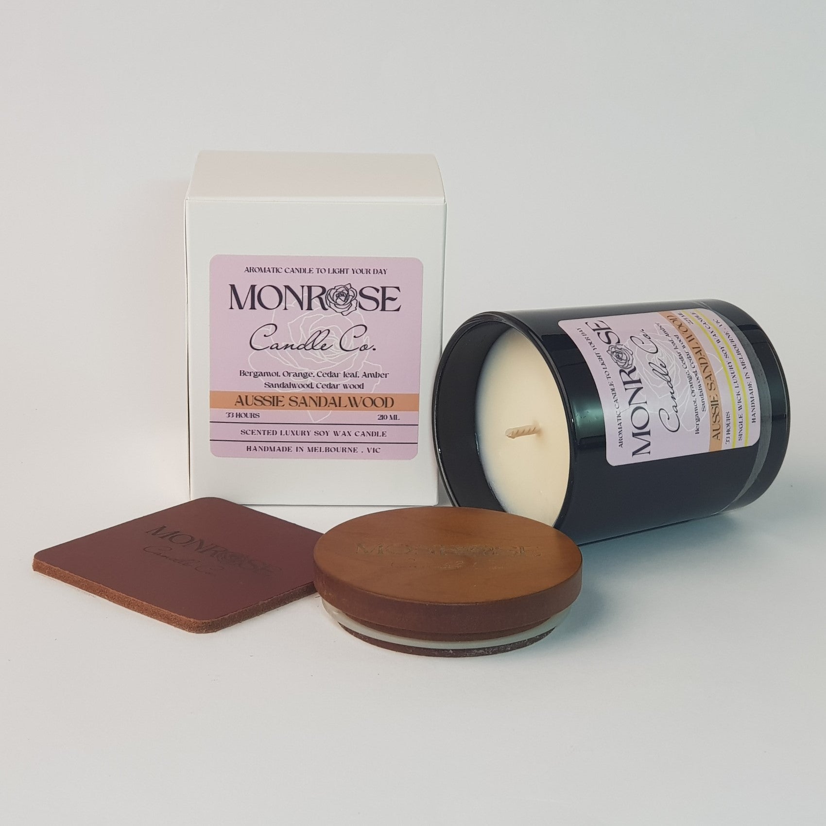 Side view of a container candle with "Australian Sandalwood" fragrance in black glass jar and a cotton wick, containing 185 grams of soy wax and offering 33 hours of burn time.