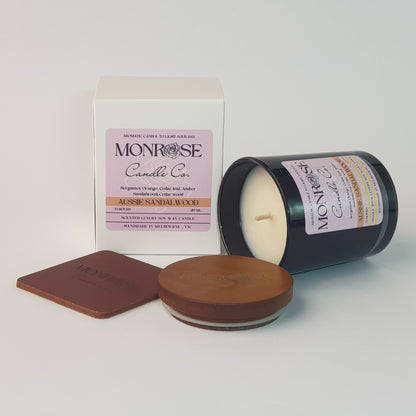 Side view of a container candle with "Australian Sandalwood" fragrance in black glass jar and a cotton wick, containing 185 grams of soy wax and offering 33 hours of burn time.