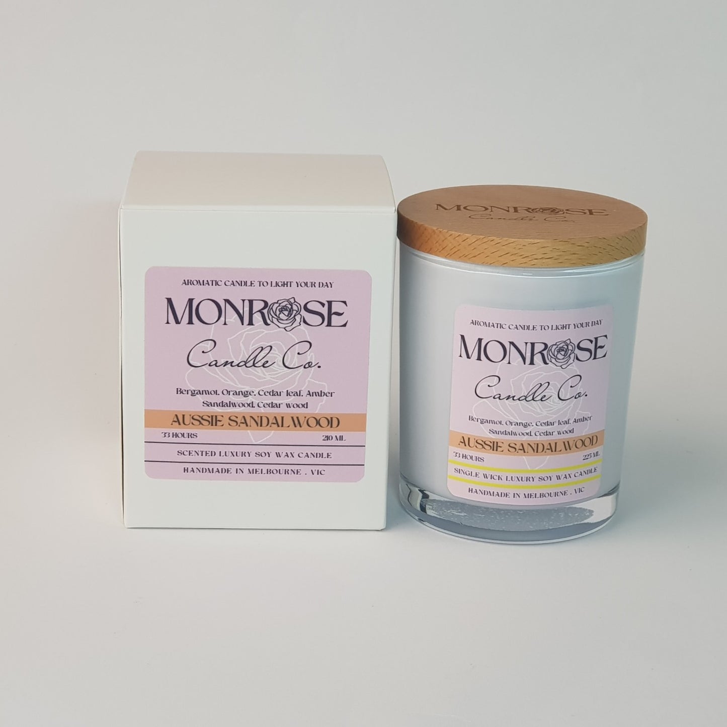 Front view of a container candle with "Australian Sandalwood" fragrance in black glass jar and a cotton wick, containing 185 grams of soy wax and offering 33 hours of burn time.