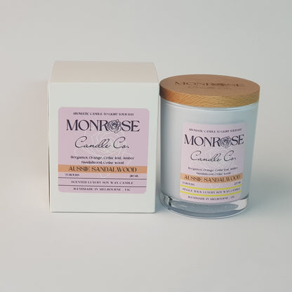 Front view of a container candle with "Australian Sandalwood" fragrance in black glass jar and a cotton wick, containing 185 grams of soy wax and offering 33 hours of burn time.