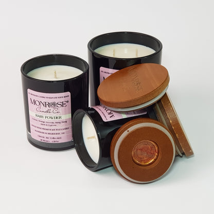 Front view of a candle collection in black jars with "Baby powder" fragrance and a cotton wick.