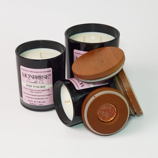 Front view of a candle collection in black jars with "Baby powder" fragrance and a cotton wick.