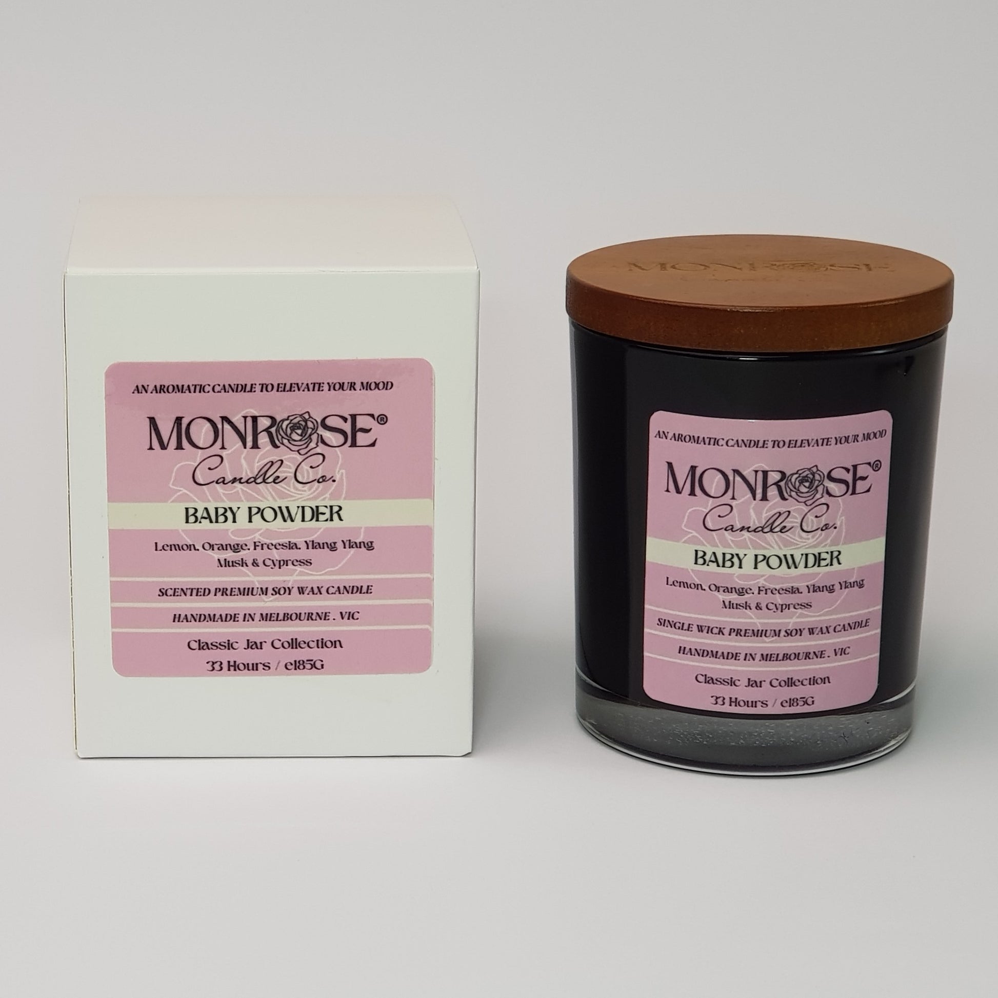 Front view of a black jar candle with "Baby powder" fragrance and a cotton wick, containing 185 grams of soy wax and offering 33 hours of burn time.