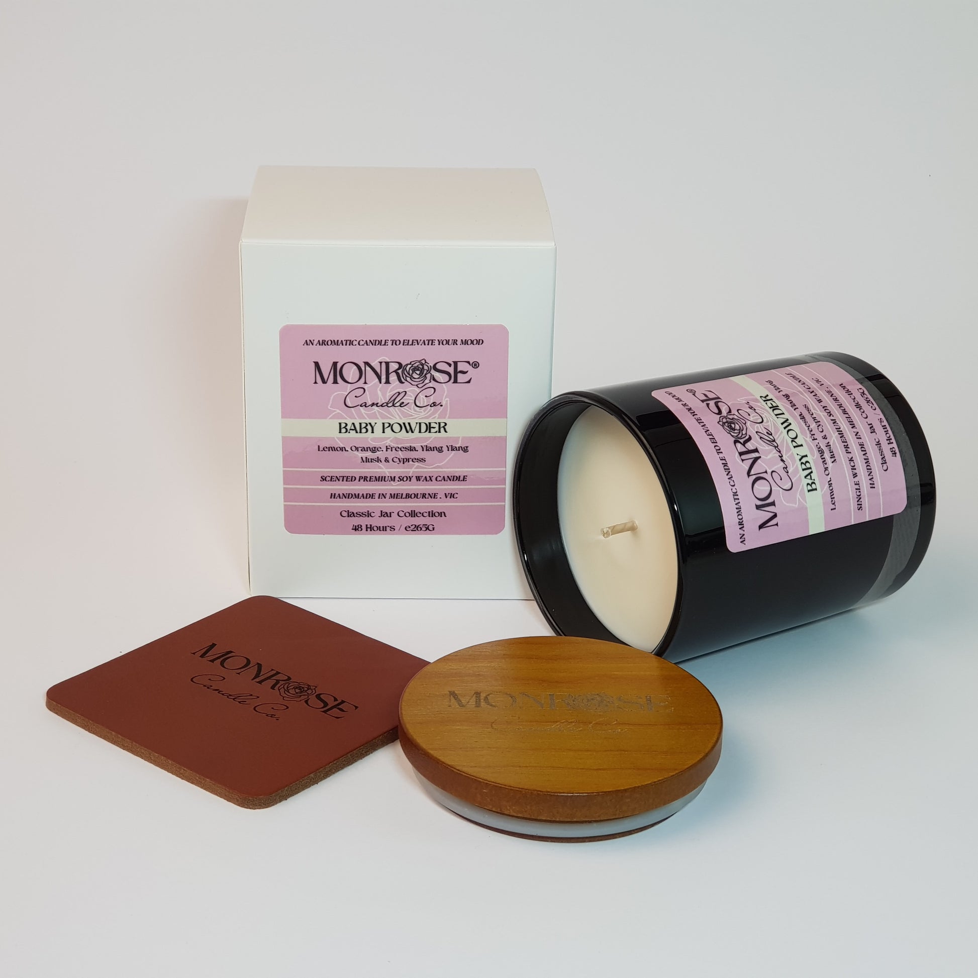 Side view of a black jar candle with "Baby powder" fragrance and a cotton wick, containing 265 grams of soy wax and offering 48 hours of burn time.