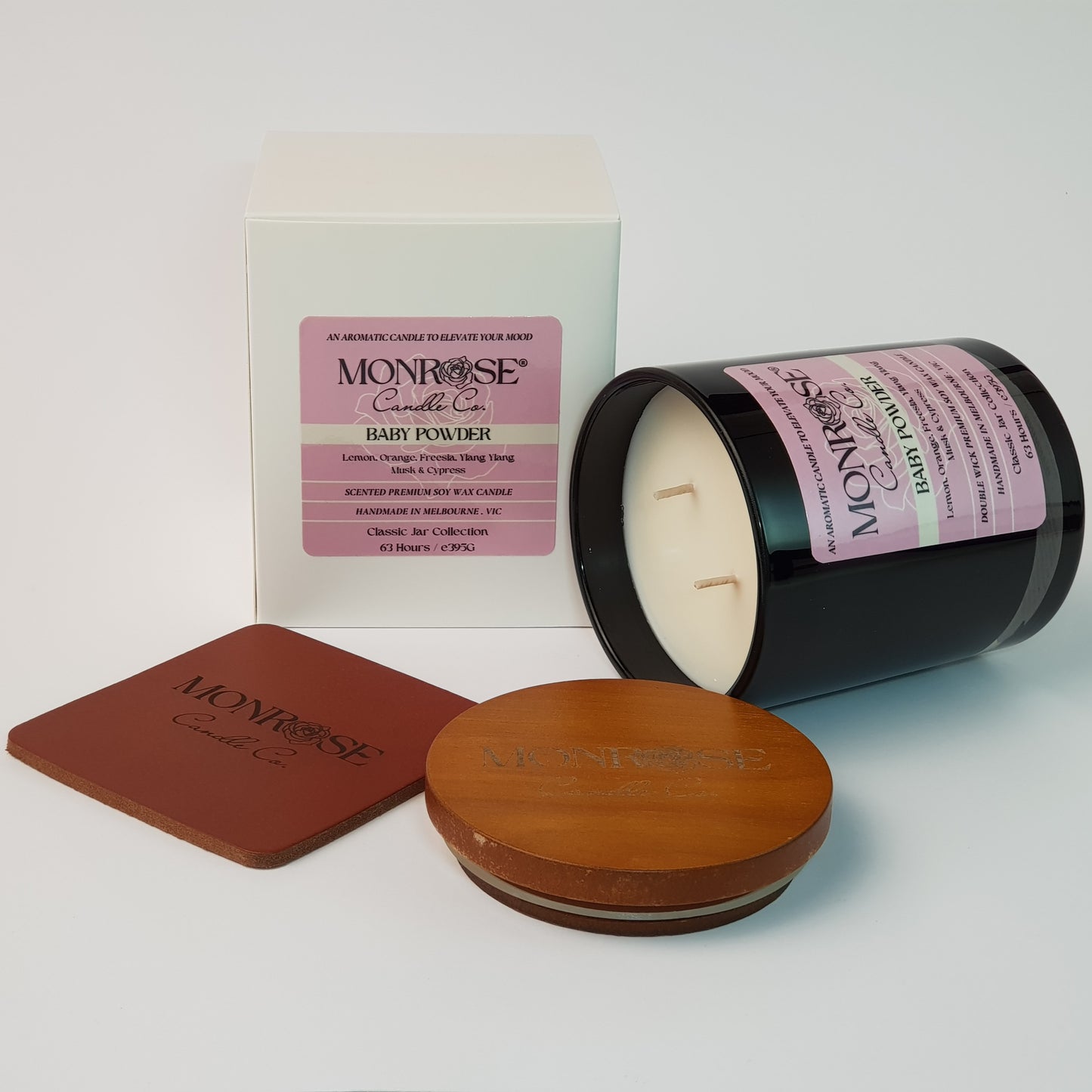 Side view of a black jar candle with "Baby powder" fragrance and double cotton wicks, containing 395 grams of soy wax and offering 63 hours of burn time.