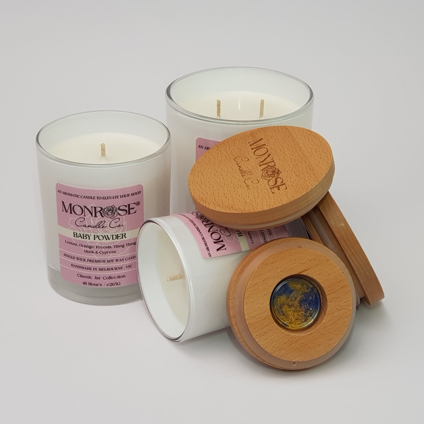 Front view of a candle collection in White jars with "Baby powder" fragrance and a cotton wick.