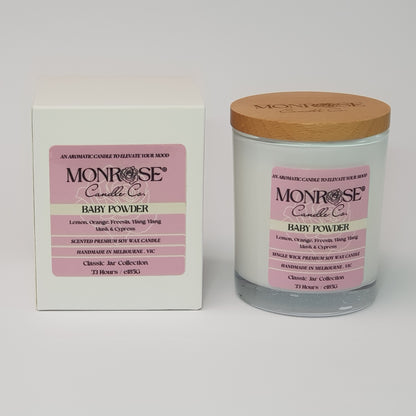 Front view of a white jar candle with "Baby powder" fragrance and a cotton wick, containing 185 grams of soy wax and offering 33 hours of burn time.