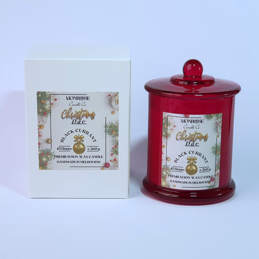 This is a front view of a red jar candle with "Black Currant" fragrance and a cotton wick, containing 260 grams of soy wax and offering 45 hours of burn time.