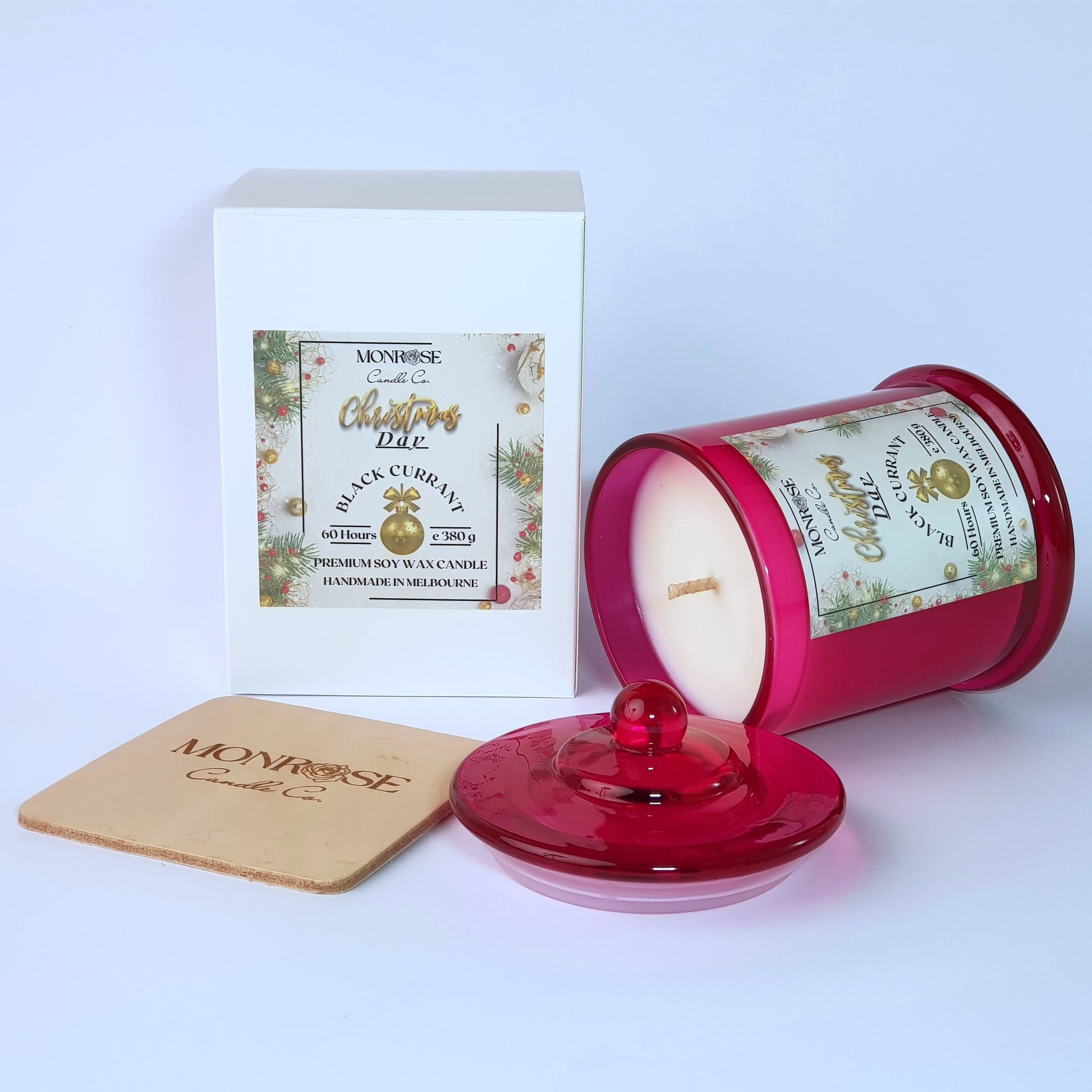 Side view of a red jar candle with 
"Black Currant" fragrance and a cotton wick, containing 380 grams of soy wax and offering 60 hours of burn time.