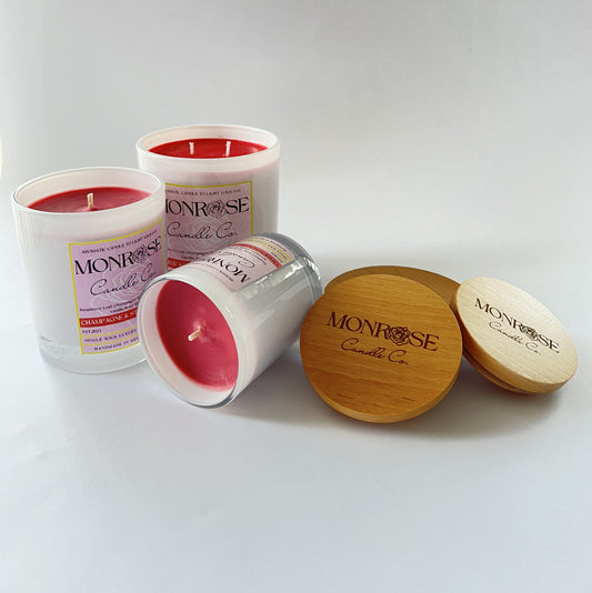 Front view of a white jar candle collection with "champagne and strawberries" fragrance and a cotton wicks.