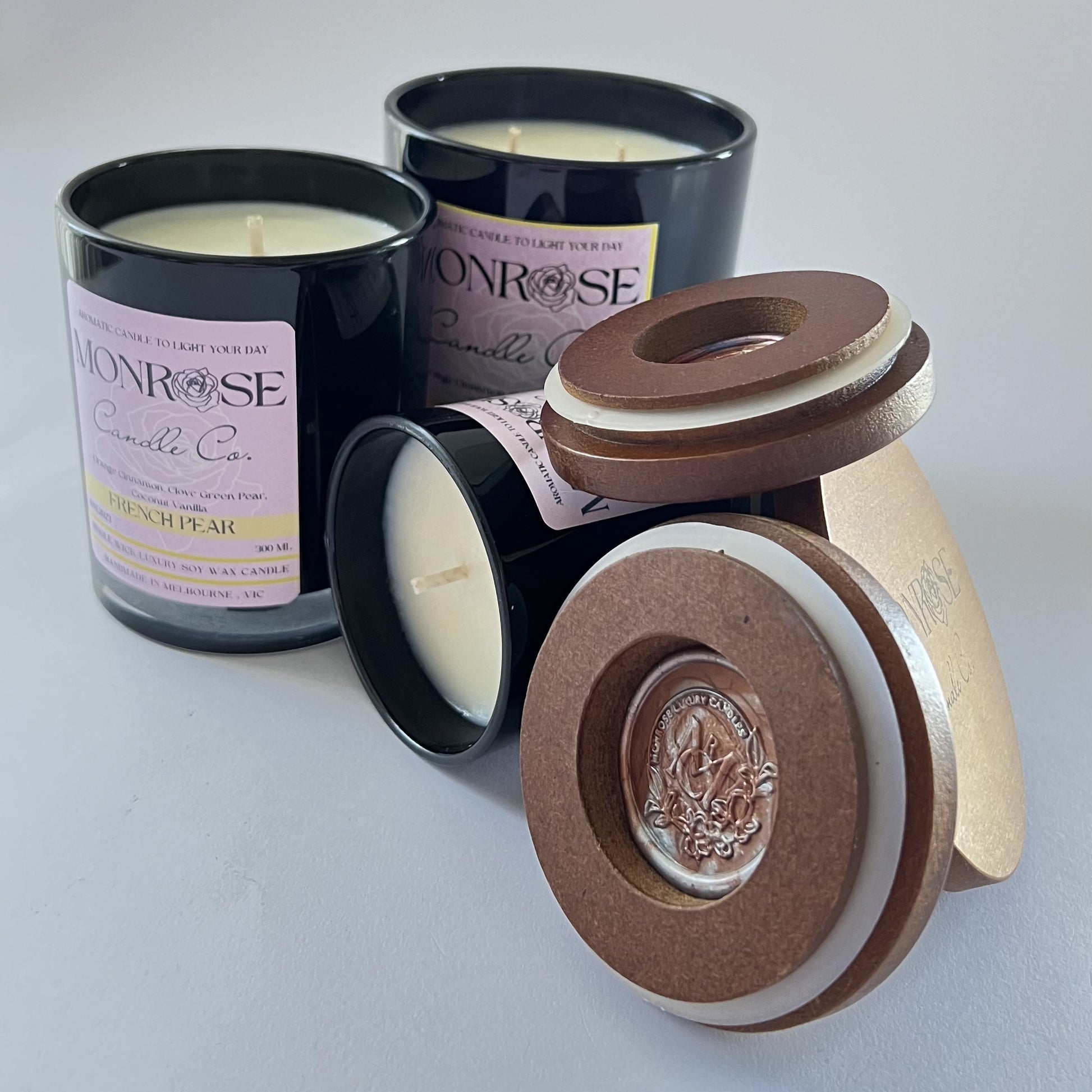 "Front view of french pear fragrance candle collection in black jars and  cotton wicks."