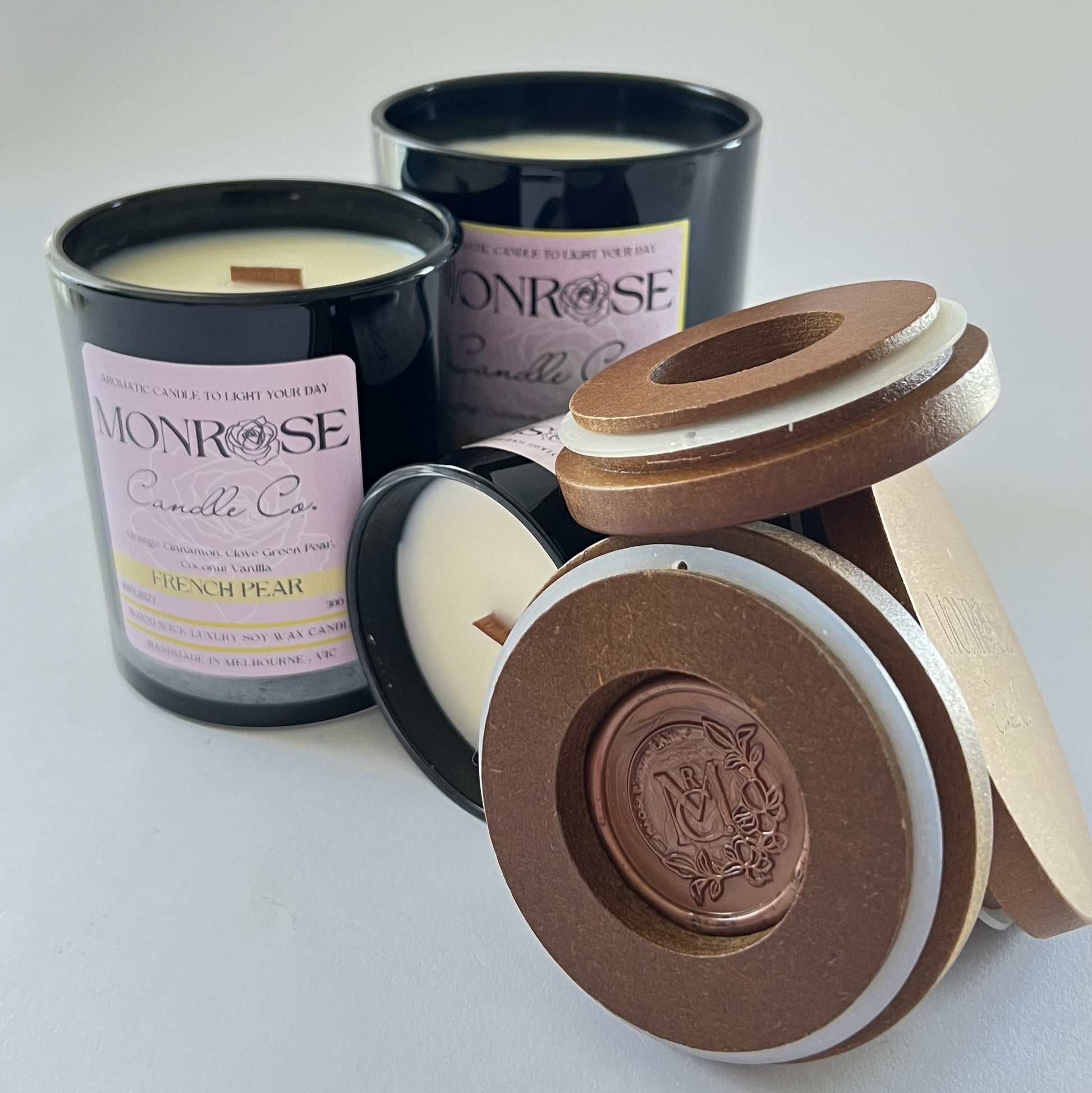 "Front view of french pear fragrance candle collection in black jars and  wood wicks."