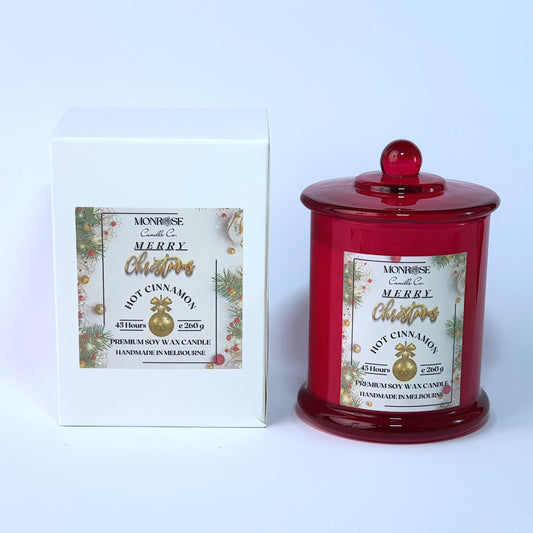 Front view of a red jar candle with 
"Hot Cinnamon" fragrance and a cotton wick, containing 260 grams of soy wax and offering 45 hours of burn time.