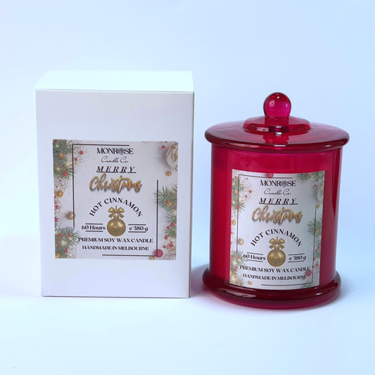 "Front view of a red jar candle with 
"Hot Cinnamon" fragrance and a cotton wick, containing 380 grams of soy wax and offering 60 hours of burn time."