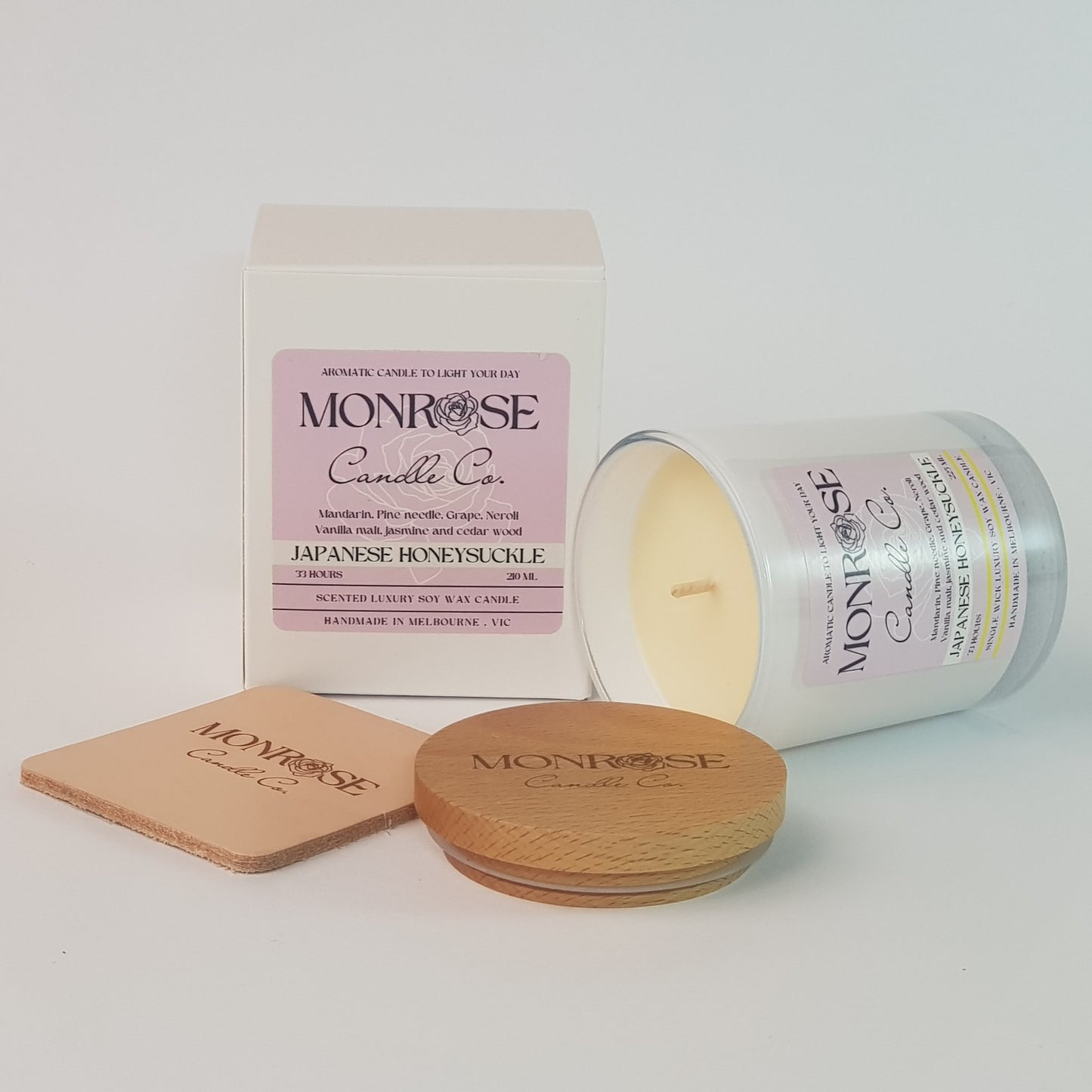 Side view of a white jar candle with "Japanese honeysuckle" fragrance and a cotton wick, containing 185 grams of soy wax and offering 33 hours of burn time.