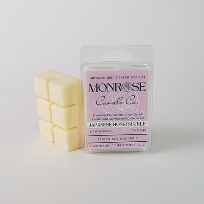 "This is the side view of a 6 pack soy wax melt, featuring a cream solid wax melt standing on the left of the packaging. The fragrance of the wax melt is Japanese honeysuckle and contains 70 grams of soy wax and it is hand crafted in Melbourne, Australia."