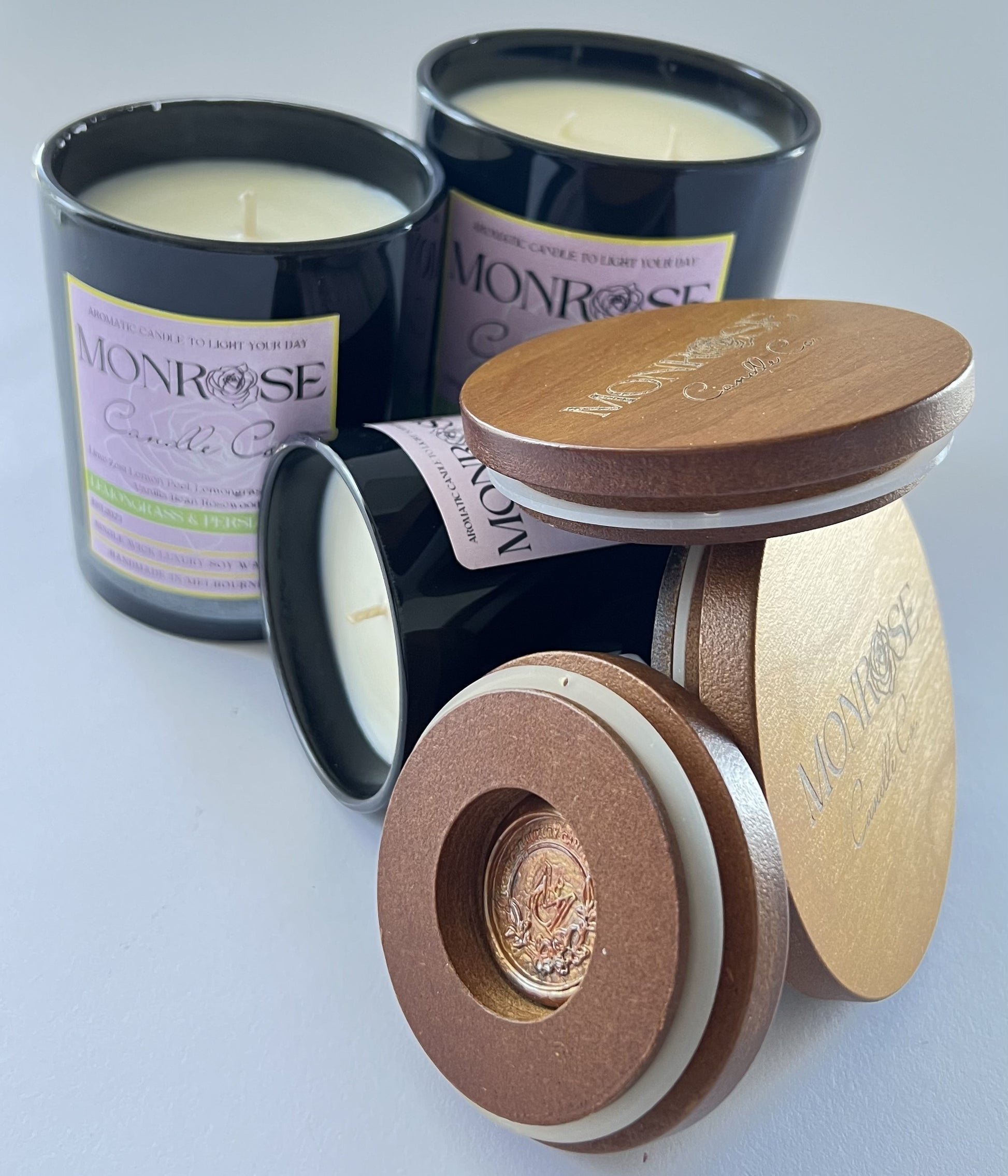Front view of "Lemongrass & Persian lime" fragrance candle collection in black jars with cotton wicks.