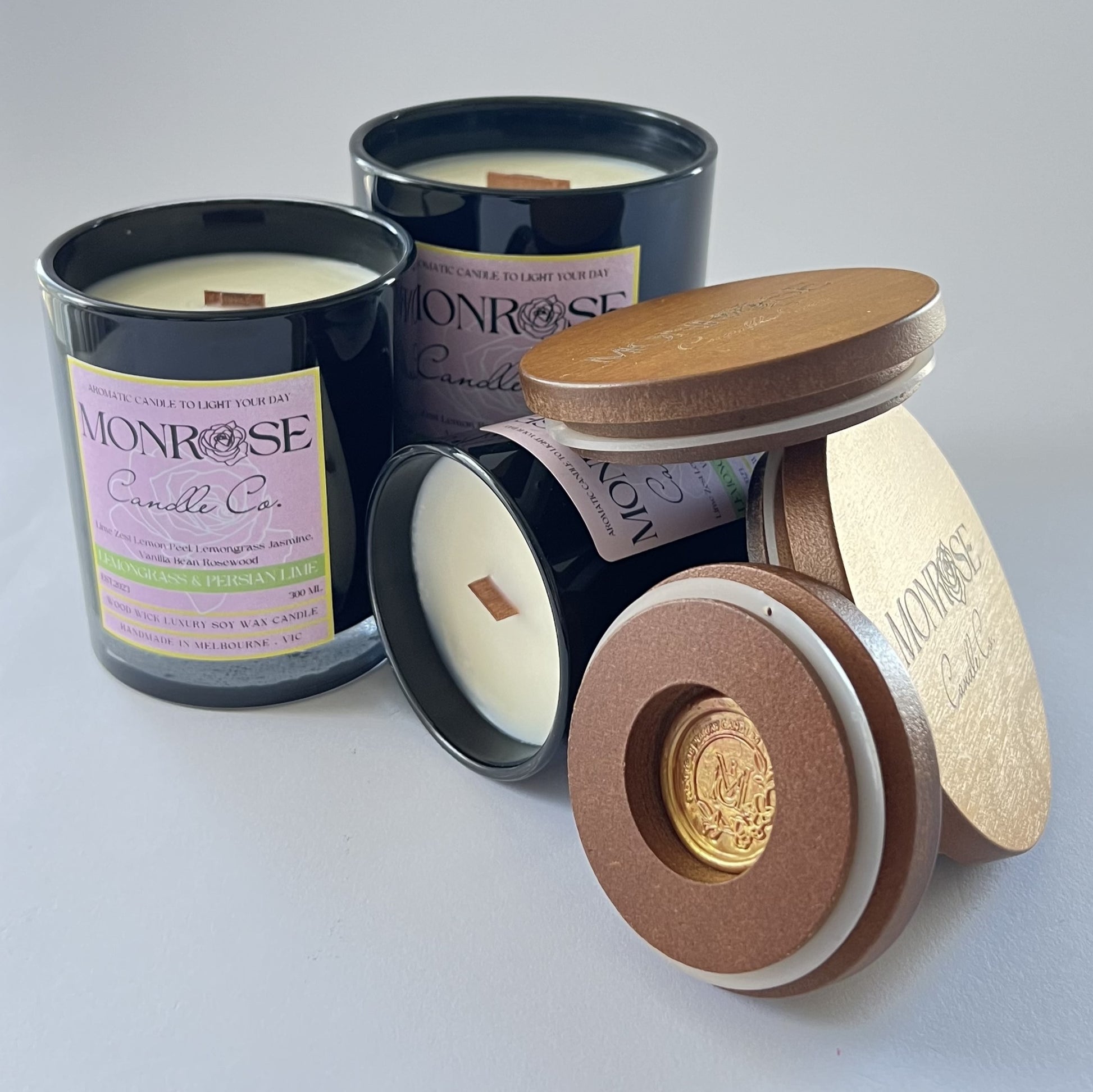 Front view of "Lemongrass & Persian lime" fragrance candle collection in black jars with wood wicks.