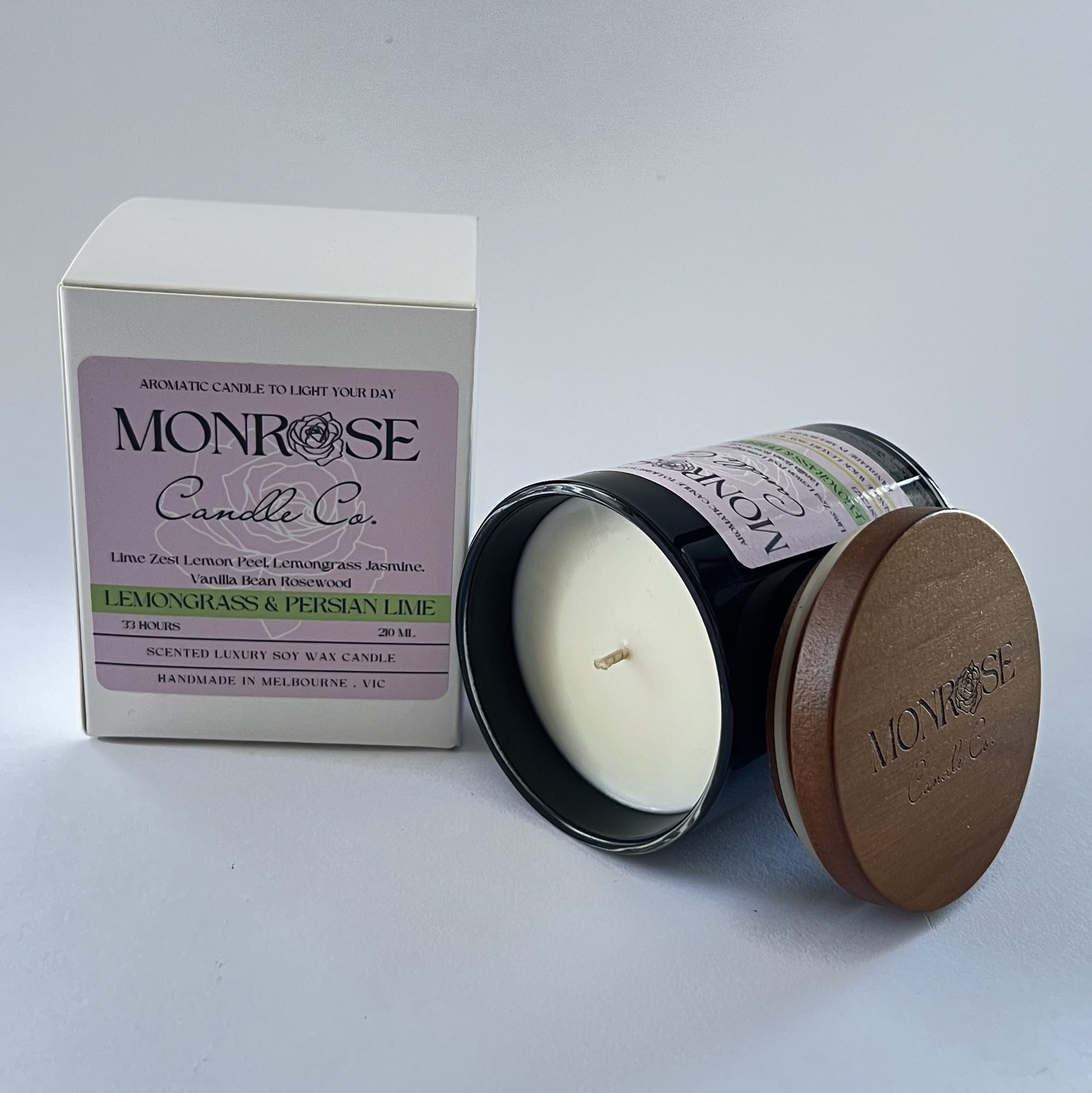 Side view of a black jar candle with "Lemongrass & Persian lime" fragrance and a cotton wick, containing 185 grams of soy wax and offering 33 hours of burn time.