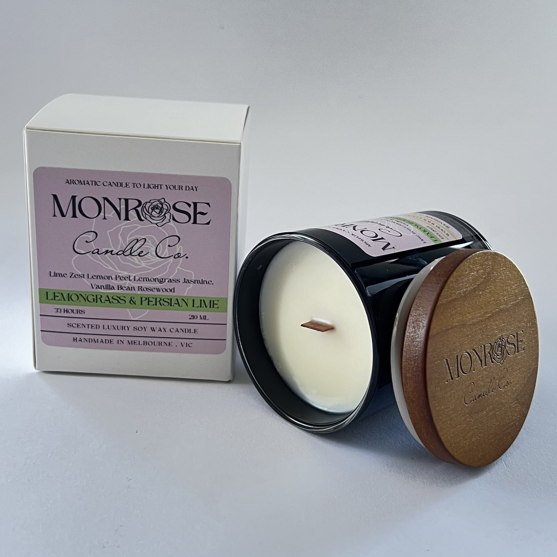 Side view of a black jar candle with "Lemongrass & Persian lime" fragrance and wood wick, containing 185 grams of soy wax and offering 33 hours of burn time.