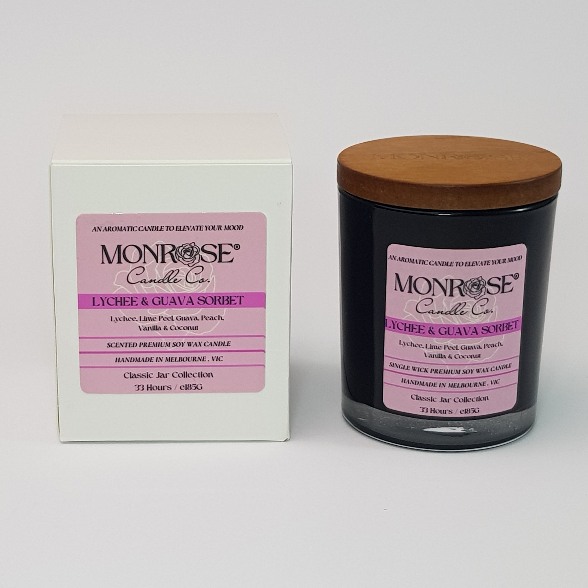 Front view of a container candle with "Lychee & guava sorbet" fragrance in black glass jar and a cotton wick, containing 185 grams of soy wax and offering 33 hours of burn time.
