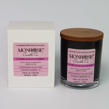 Front view of a container candle with "Lychee & guava sorbet" fragrance in black glass jar and a cotton wick, containing 265 grams of soy wax and offering 48 hours of burn time.