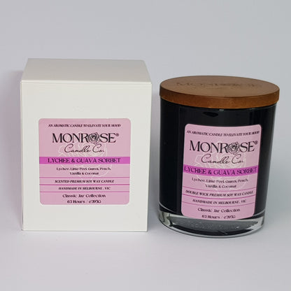 Front view of a container candle with "Lychee & guava sorbet" fragrance in black glass jar and double cotton wicks, containing 395 grams of soy wax and offering 63 hours of burn time.