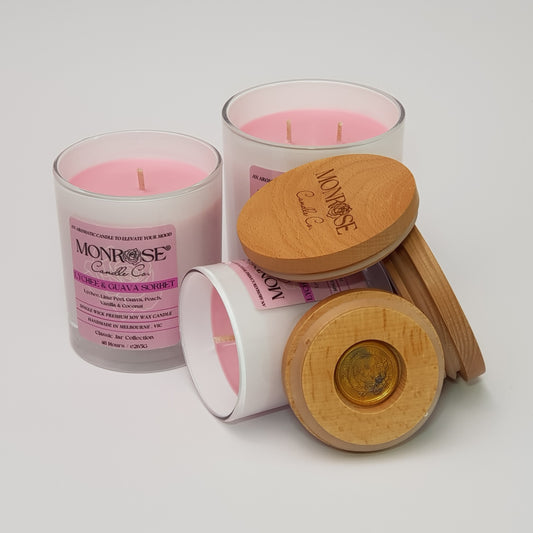 Front view of "Lychee and guava sorbet" fragrance candle collection in white jars with cotton wicks.